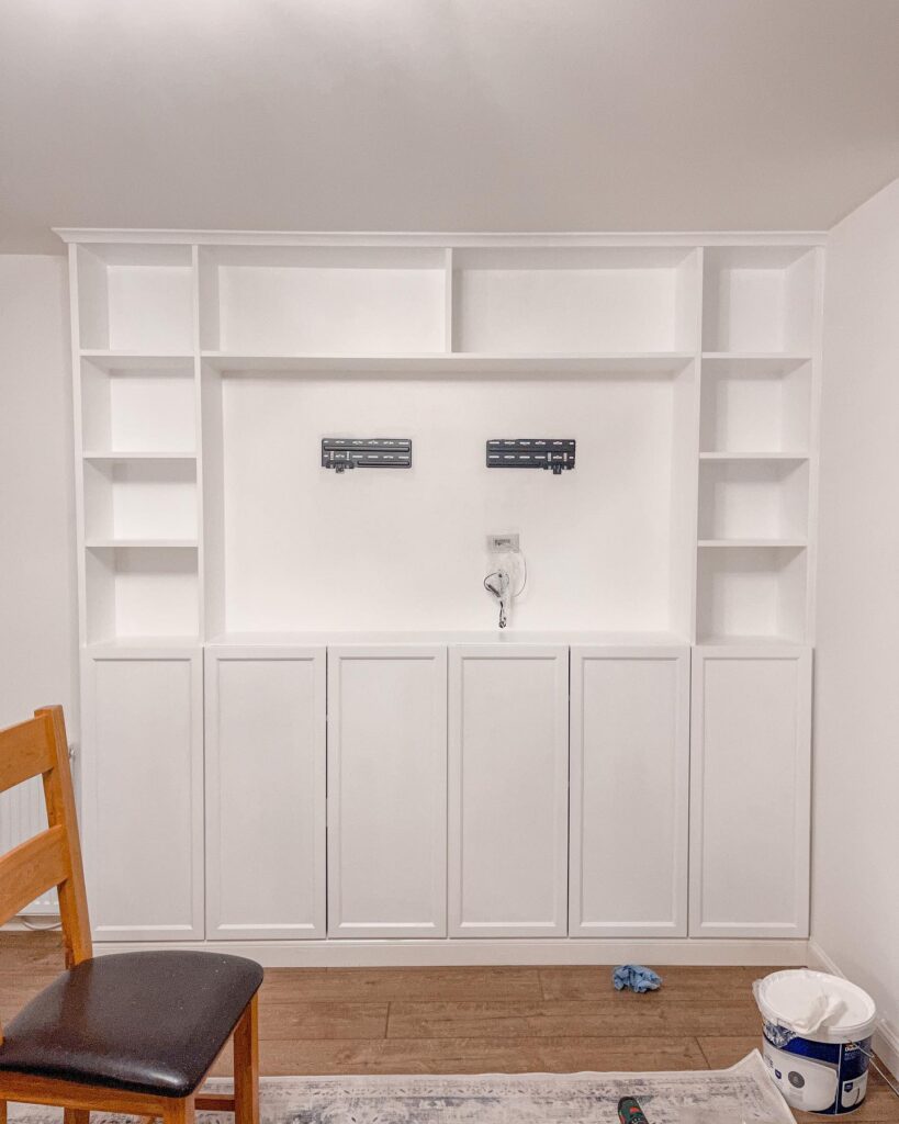 painted ikea billy bookcase media wall with tv wall mount bracket installed and cables routed through the wall