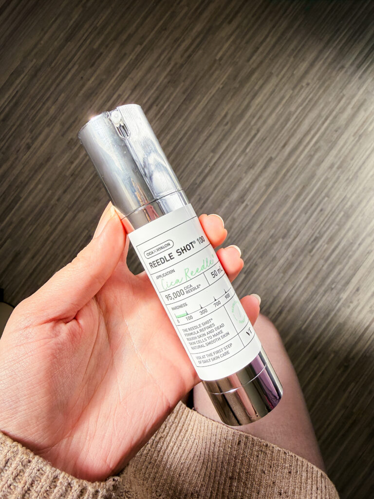 A hand holding the silver and white VT Reedle Shot 100 bottle, showing the 95,000 Cica Reedle count and hardness scale.