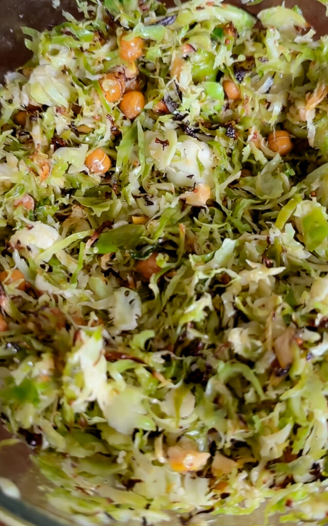 A close-up, top-down view of the completed salad featuring crispy, golden-edged shredded Brussels sprouts and roasted chickpeas mixed together.