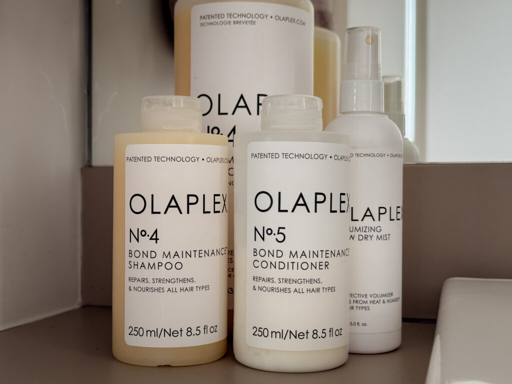 Olaplex No.4 Bond Maintenance Shampoo and No.5 Conditioner in 250ml bottles next to the Volumizing Blow Dry Mist on a bathroom counter.