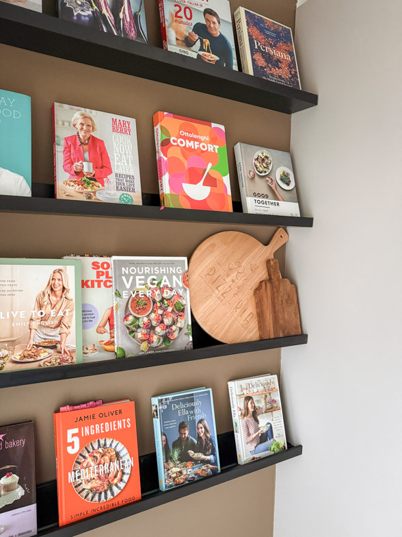 Bright coloured cookbooks against a broccoli brown wall