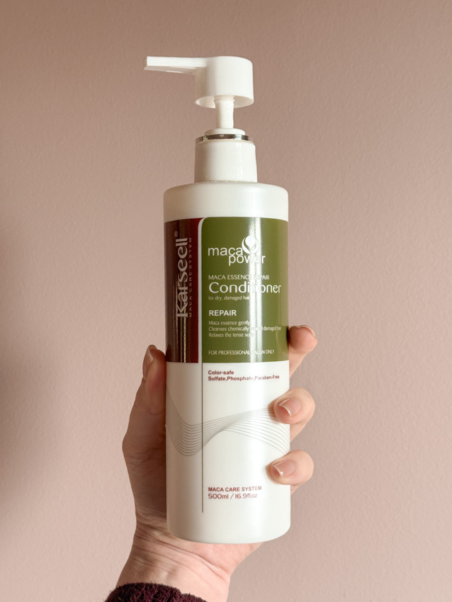 Hand holding Karseell Maca Power Repair Conditioner bottle for dry, damaged hair