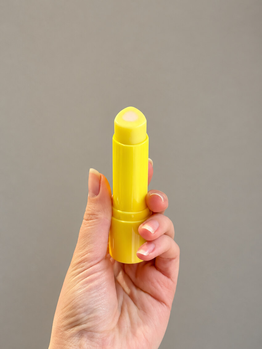 Tage retinal stick with the cap off, showing the pale balm in its yellow case